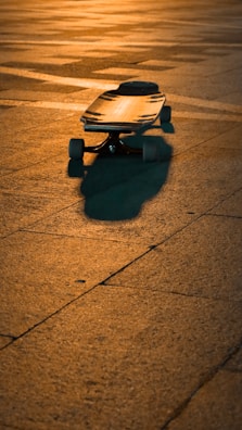 An electric longboard resting against a graffiti-covered wall, bathed in golden afternoon light.