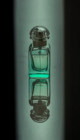 Close-up shot of a deep ripe crimson perfume bottle next to matte forest green fabric.