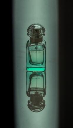 An artistic shot of a perfume bottle emitting a subtle mist, set against a gradient of navy and light pink.