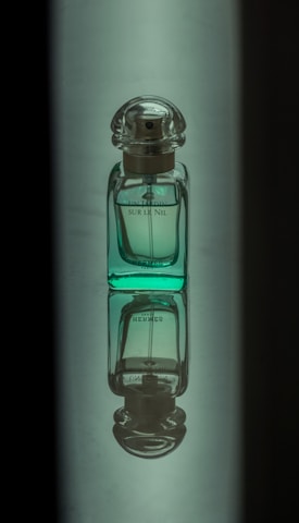 A close-up of a sleek perfume bottle designed by jaaf with a natural green backdrop.