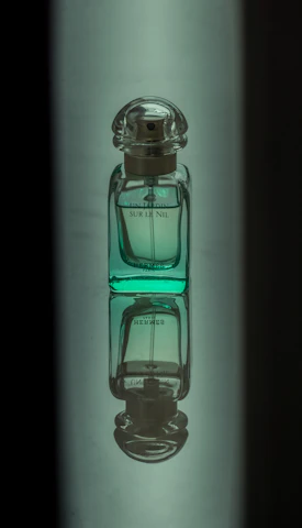 Close-up shot of a deep ripe crimson perfume bottle next to matte forest green fabric.