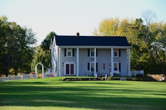 a large white house sitting on top of a lush green field