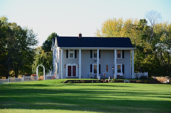 a large white house sitting on top of a lush green field