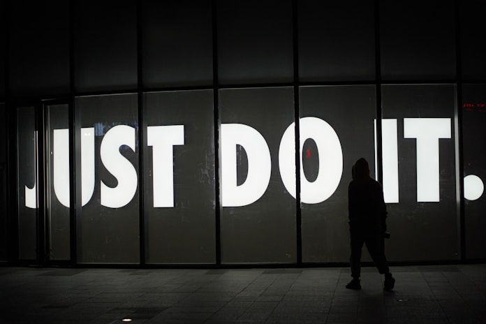 a person standing in front of a sign that says just do it