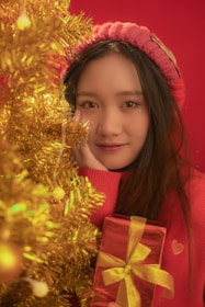 Smiling woman holding a chocotone box with a Christmas tree in the background.