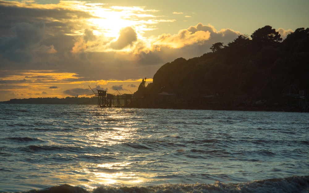 the sun is setting over the ocean with a boat in the water