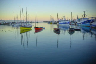 A calm harbor at dusk with tugboats gently moored alongside the dock.