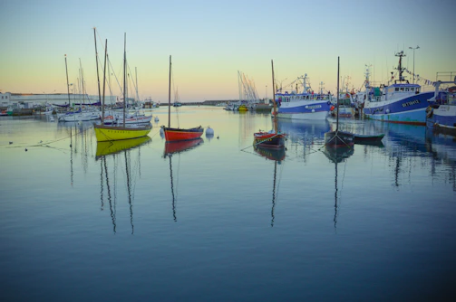 A calm harbor at dusk with tugboats gently moored alongside the dock.