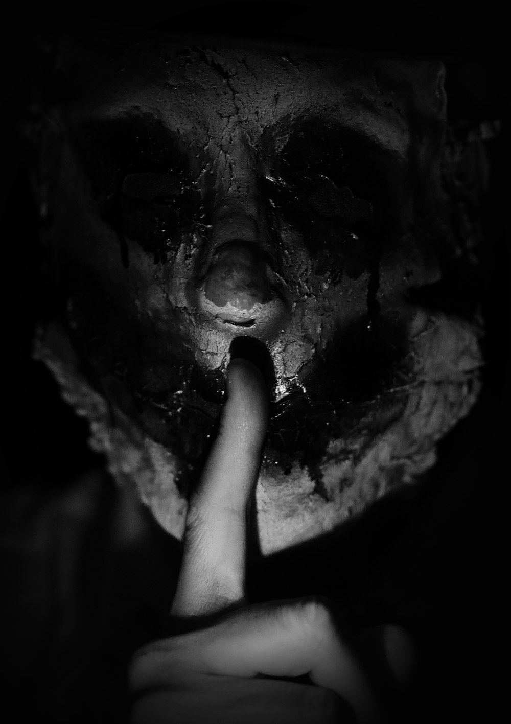uma pessoa usando uma máscara assustadora com o dedo na boca