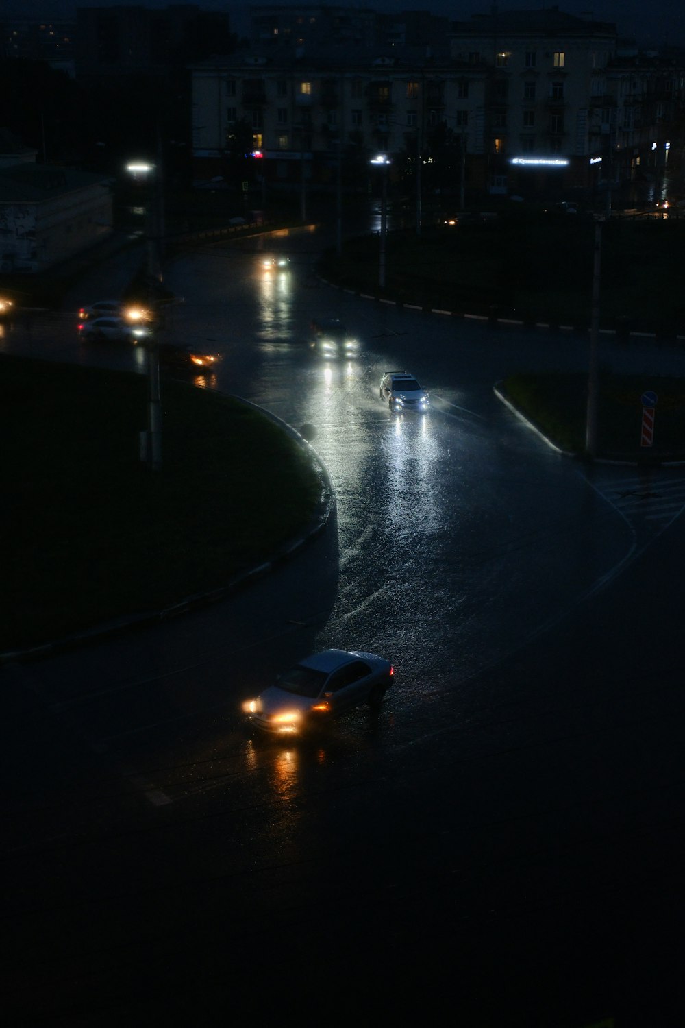 a couple of cars driving down a street at night