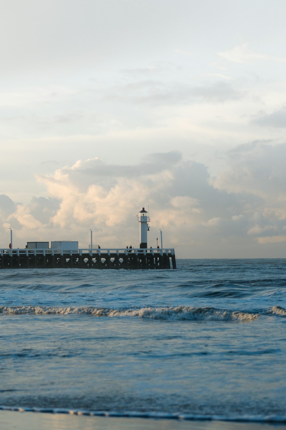 a pier with a light house in the distance