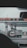 A gas station with multiple fueling pumps and several vehicles parked. Signs and logos in different languages are visible, and the setting appears overcast. Vehicles include a large truck and a white van.