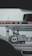 A gas station with multiple fueling pumps and several vehicles parked. Signs and logos in different languages are visible, and the setting appears overcast. Vehicles include a large truck and a white van.