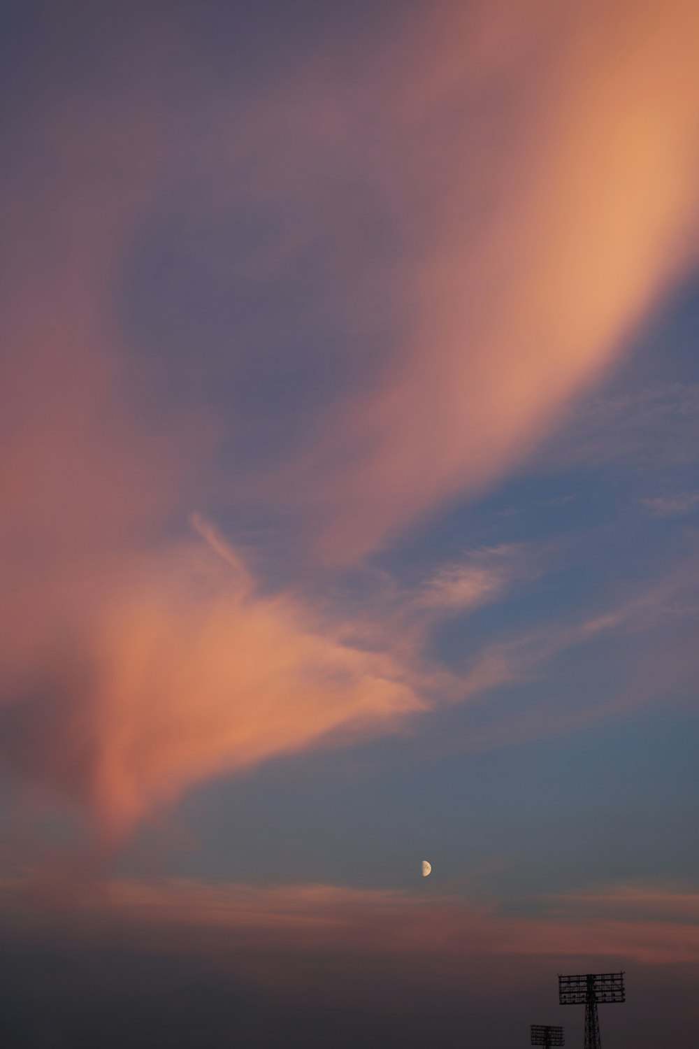 a pink and blue sky with a moon in the distance