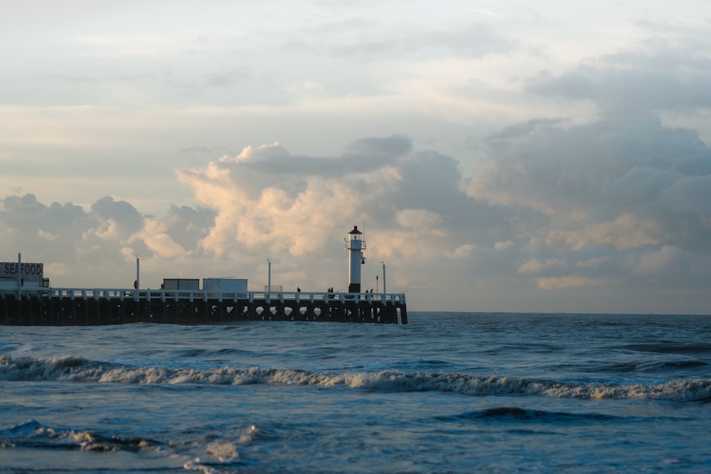 a pier with a light house in the distance