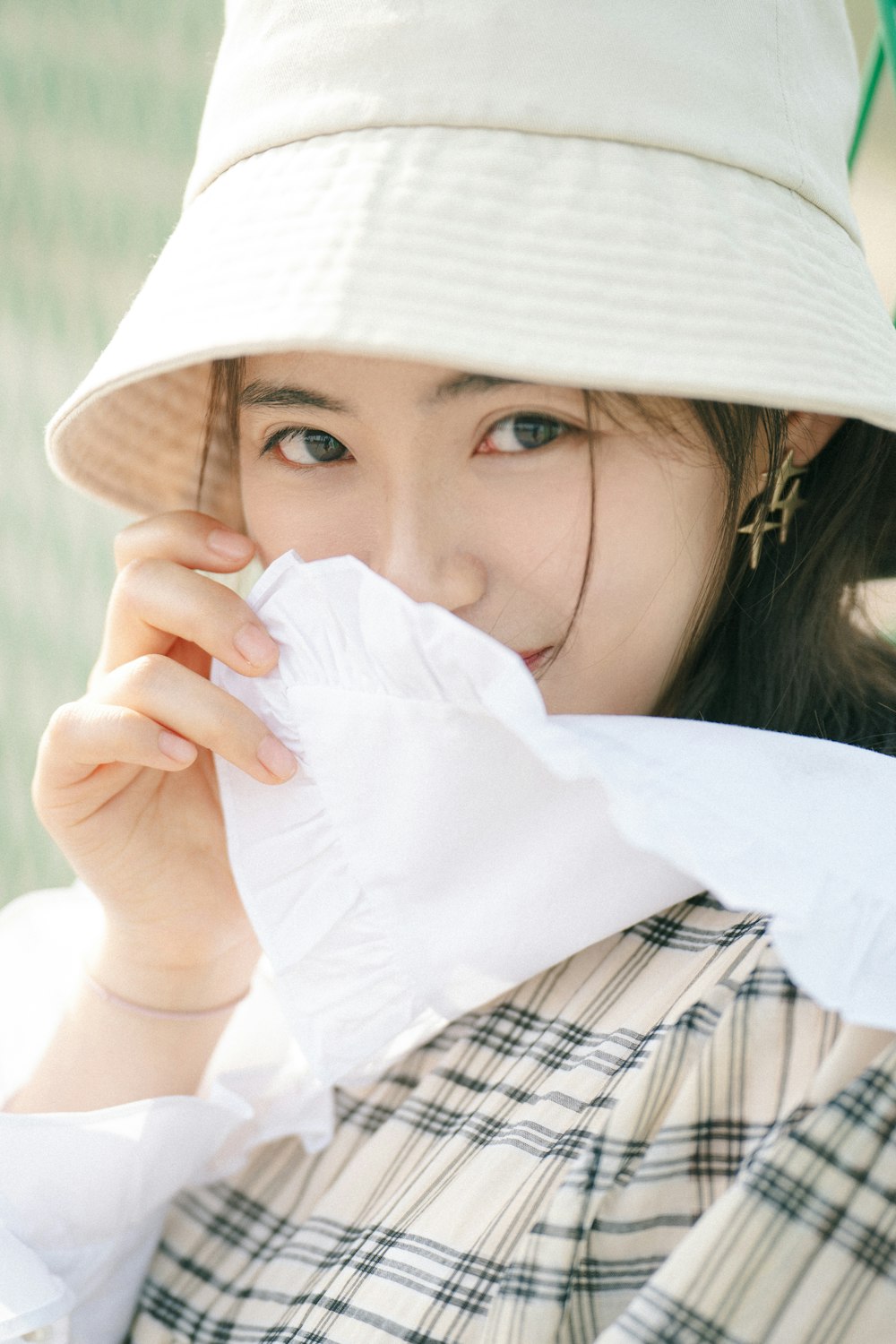 a woman wearing a hat and holding a napkin