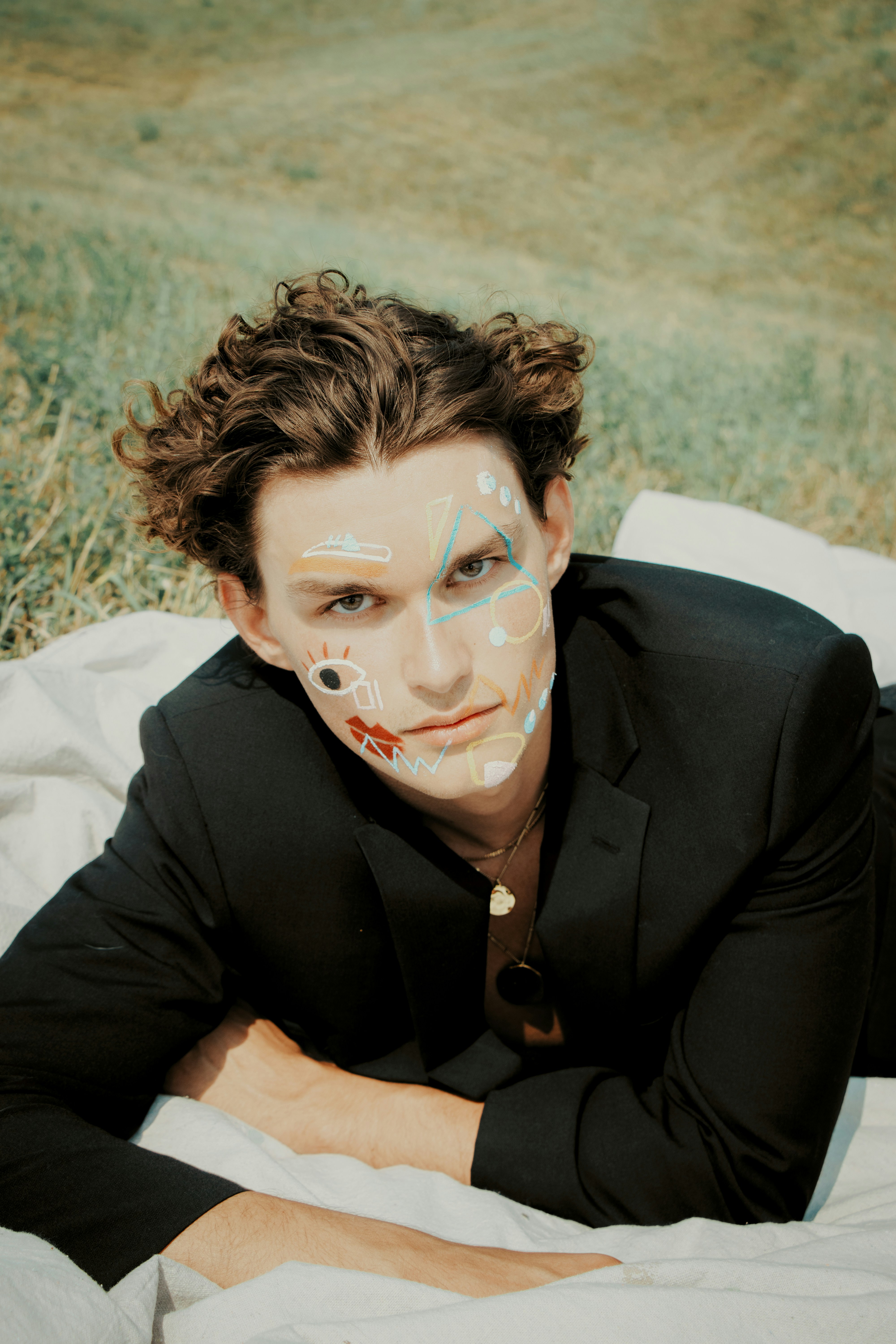 a man with a painted face laying on a blanket