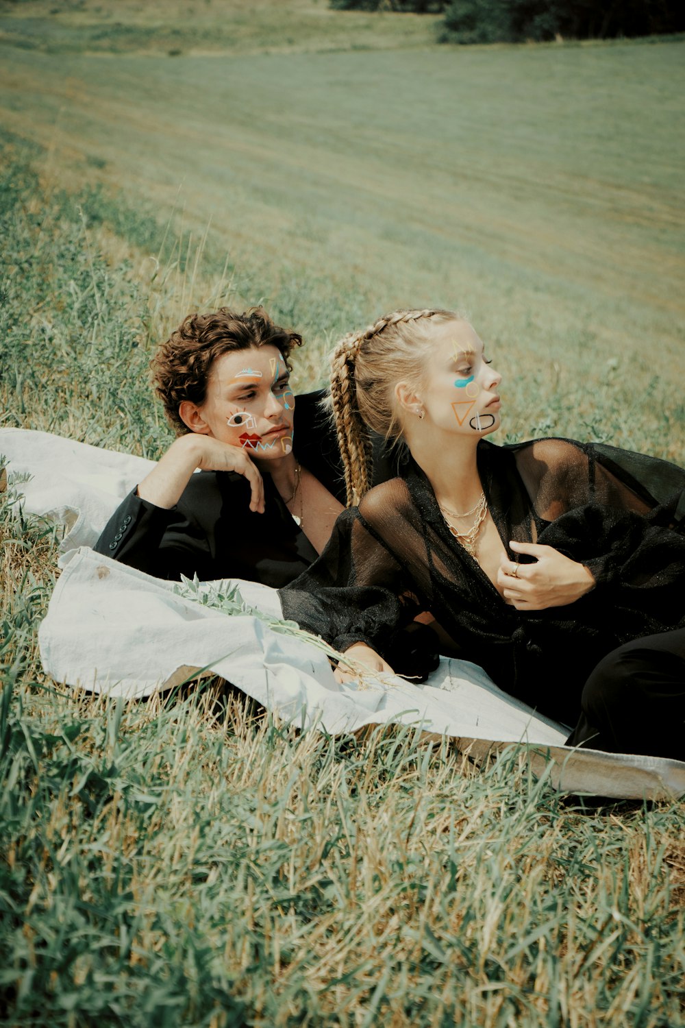 a couple of women sitting on top of a grass covered field