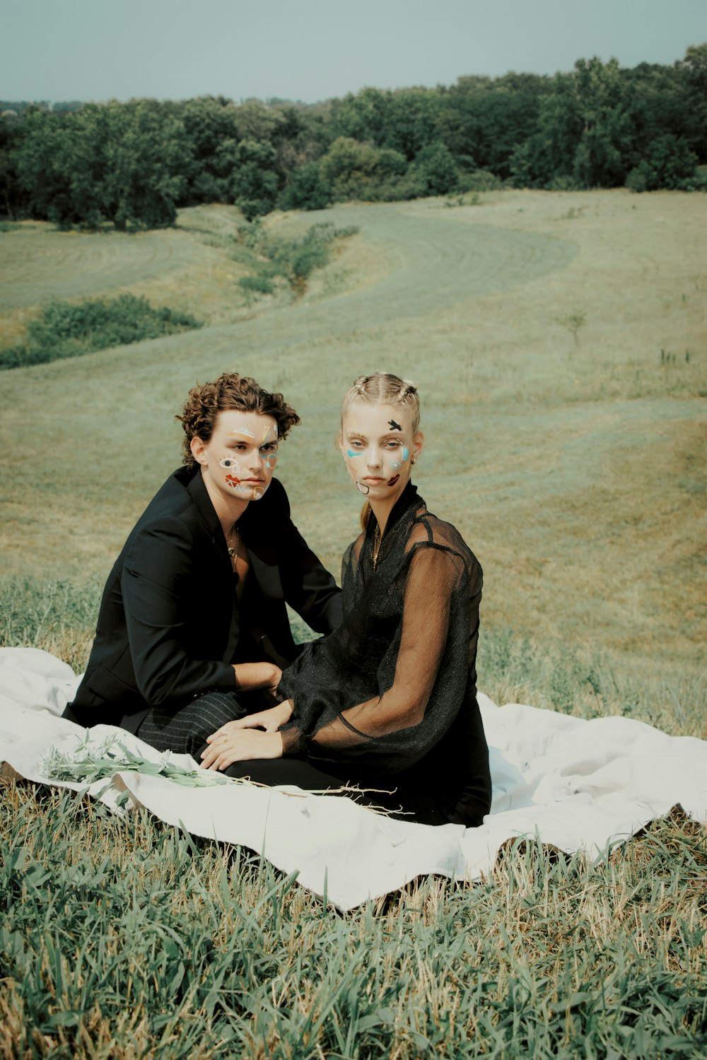 two women sitting on a blanket in a field