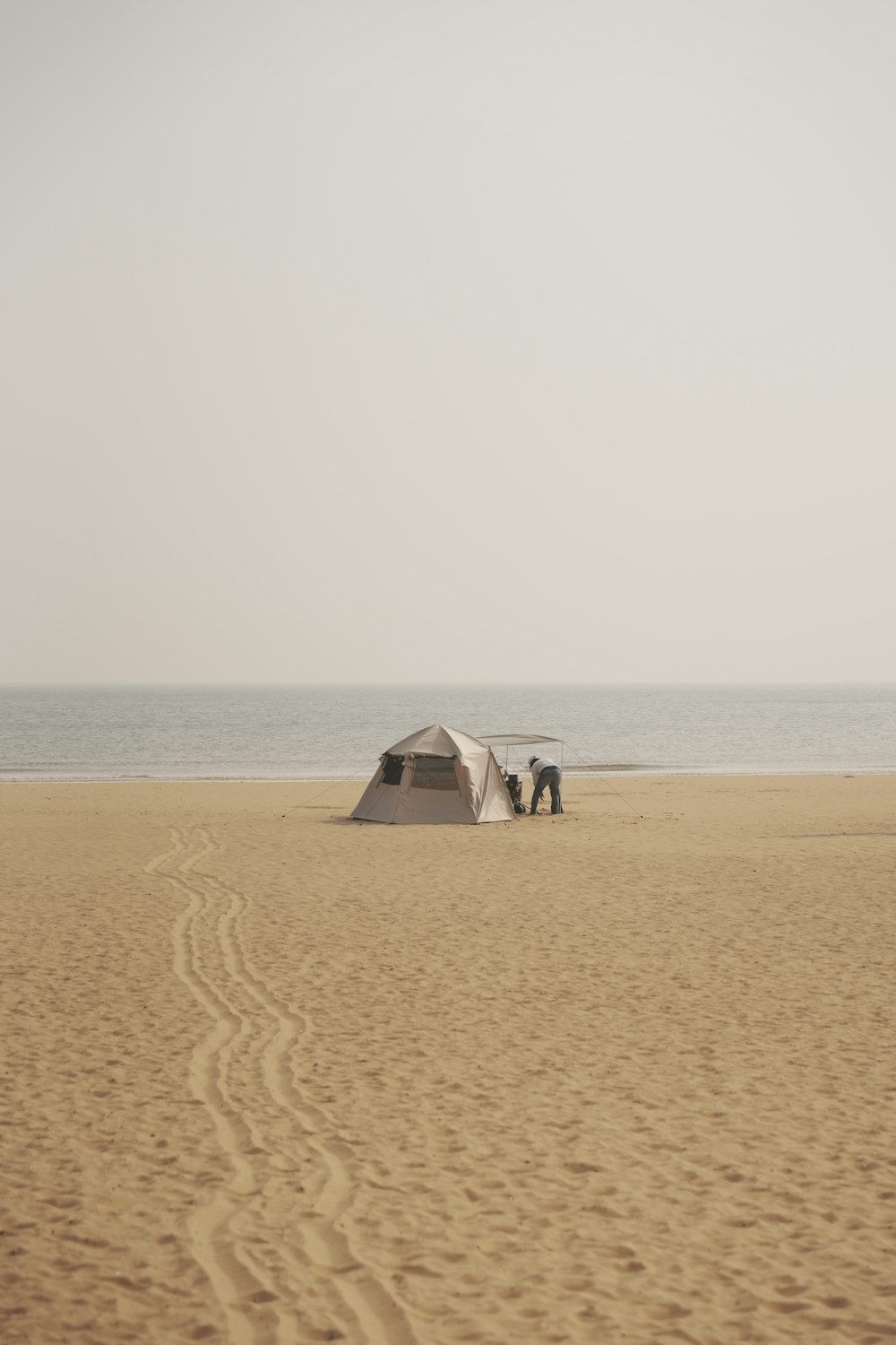 a couple of tents sitting on top of a sandy beach