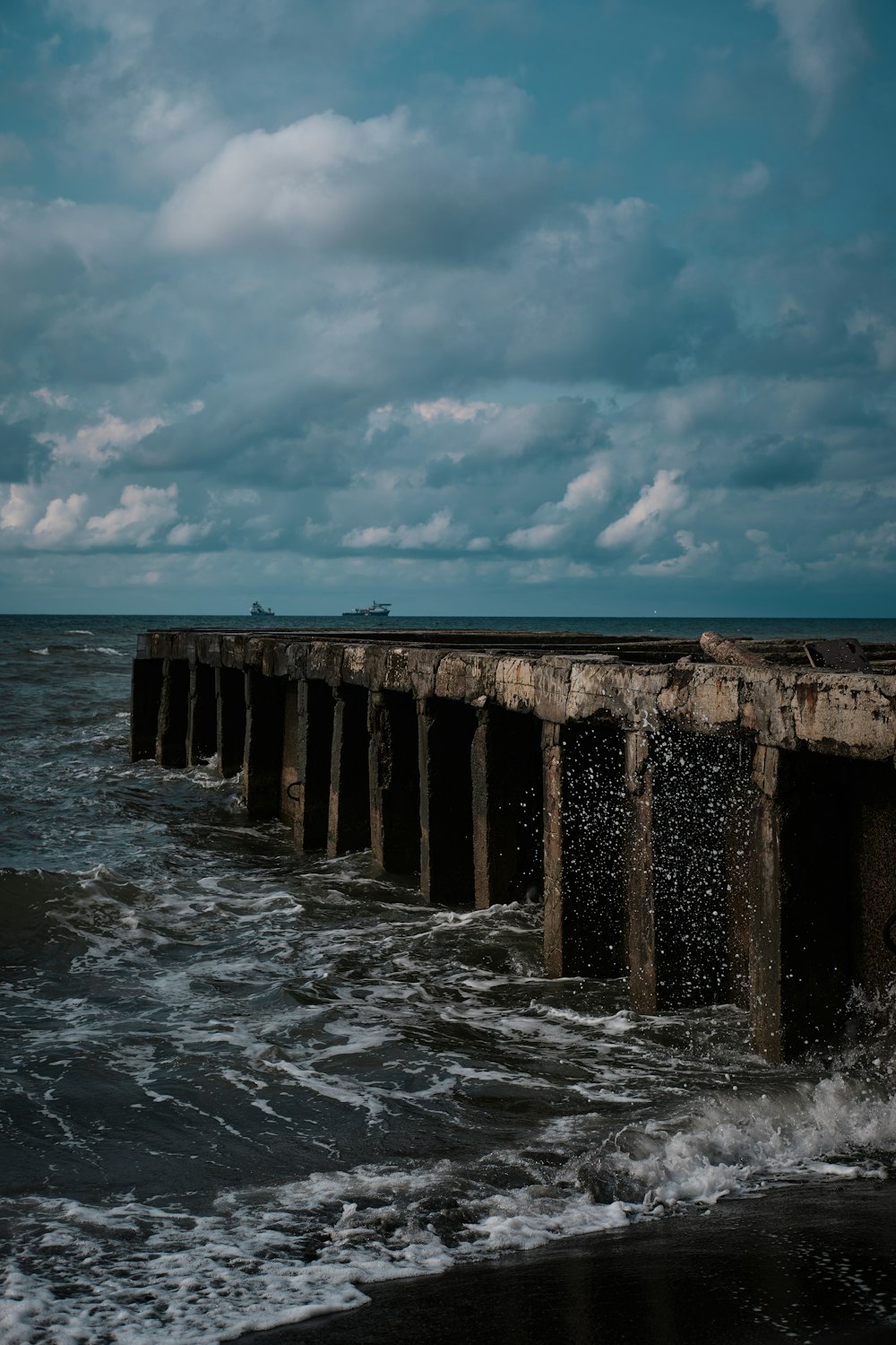 a long pier extending into the ocean under a cloudy sky