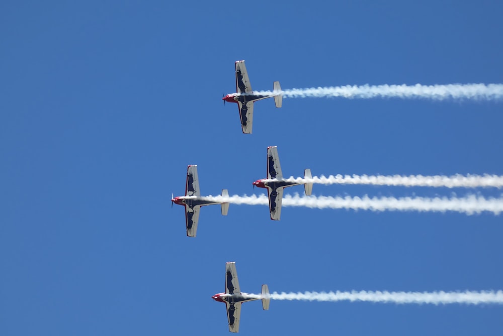 four airplanes flying in formation in a blue sky