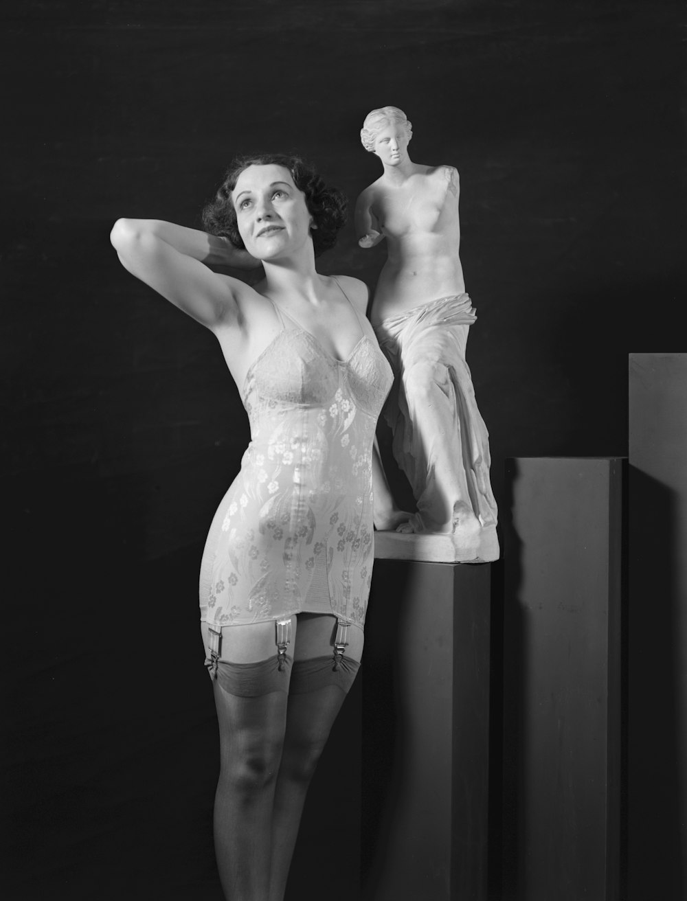 a woman standing next to a statue of a man