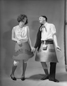 Fred and Leslie wearing quirky hats, laughing together in a schoolyard.