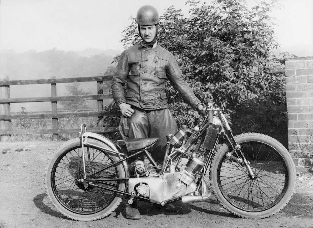 a black and white photo of a man standing next to a motorcycle