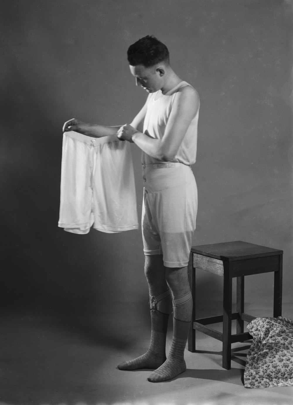 a man is holding a white shirt on a chair