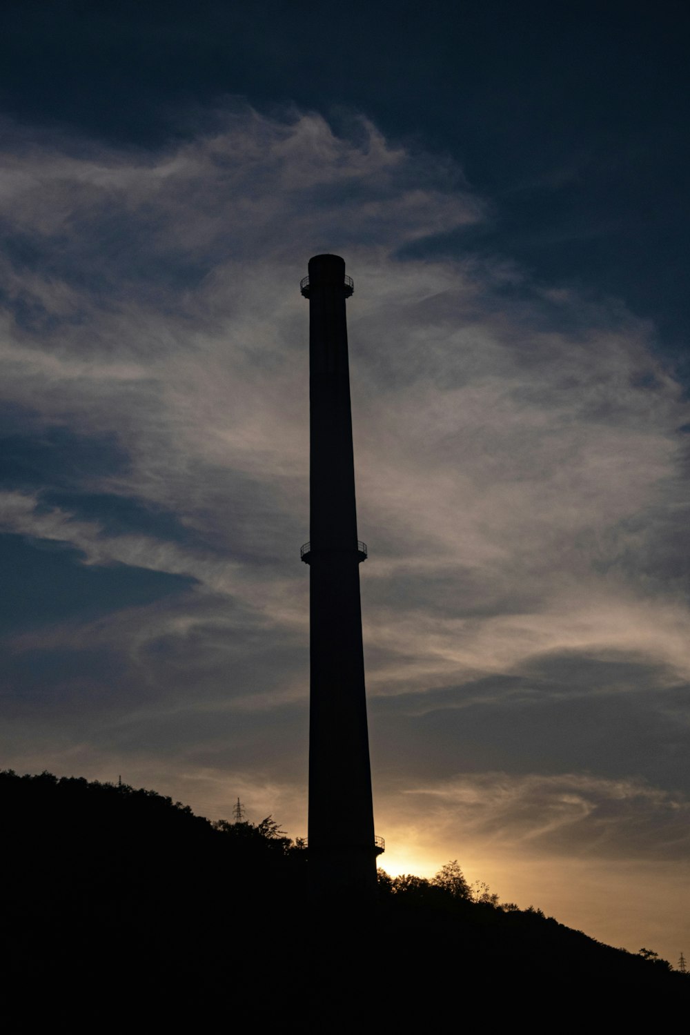 uma torre alta sentada no topo de uma colina sob um céu nublado