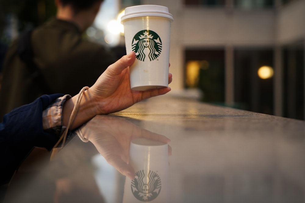a person holding a cup of starbucks coffee