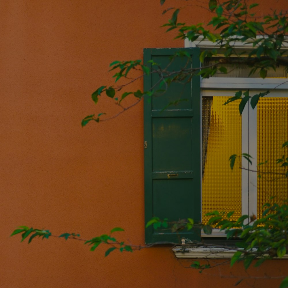 an orange building with green shutters and a window