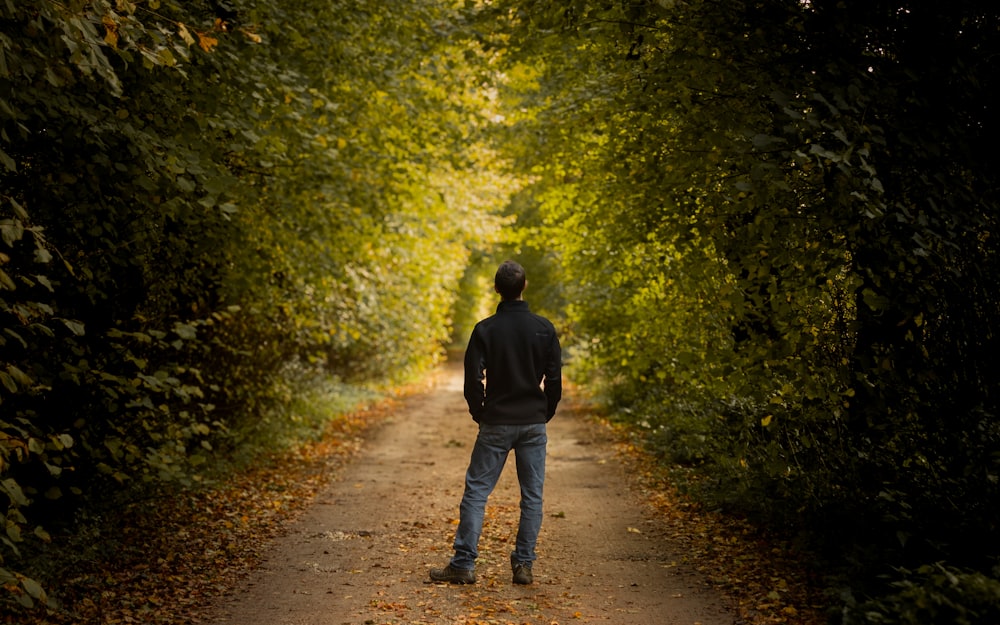 a man standing in the middle of a tunnel of trees