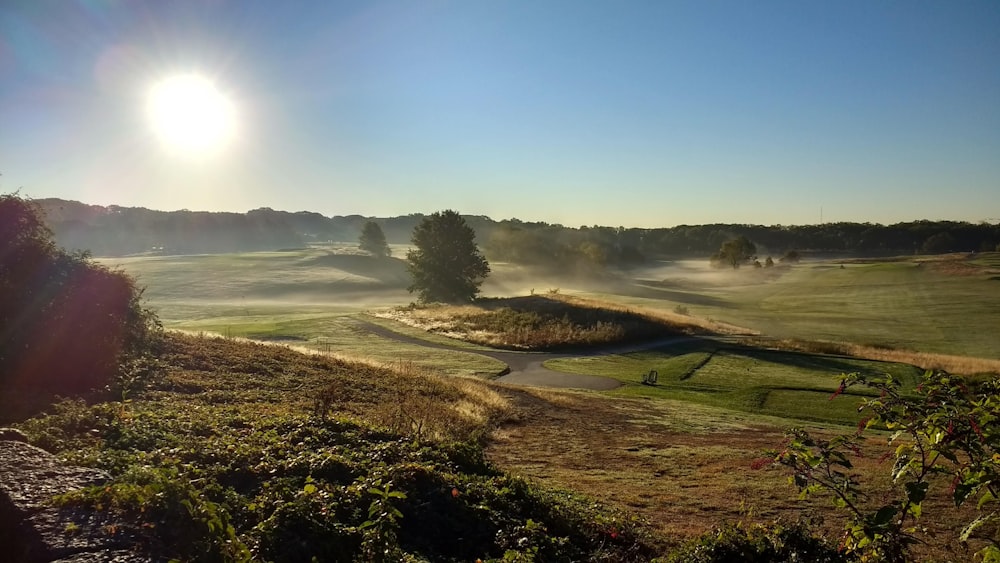 the sun is shining over a golf course