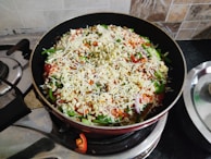 A rustic cast iron skillet sizzling with colorful vegetables on a stovetop.