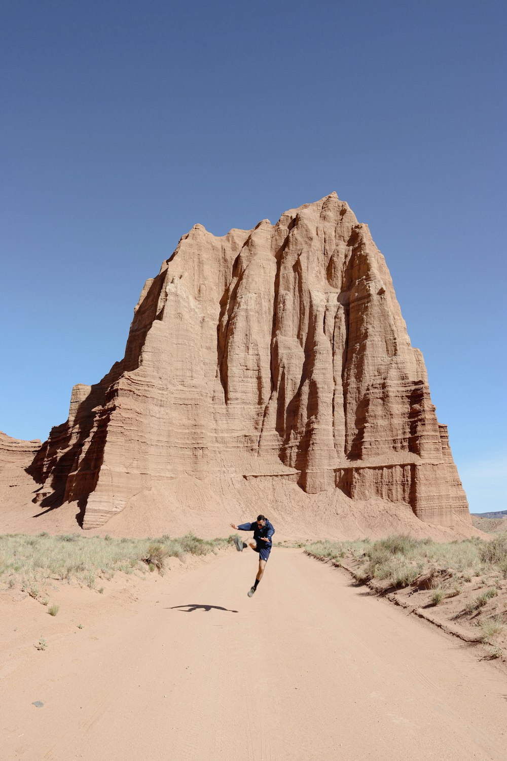 una persona che corre attraverso una strada sterrata di fronte a una montagna