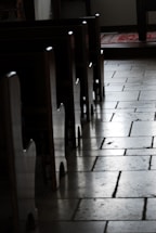 A peaceful chapel window casting soft light onto a wooden prayer bench.