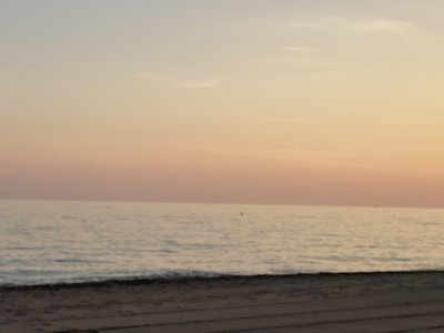 A calm beach scene with gentle waves and a pastel sunset.