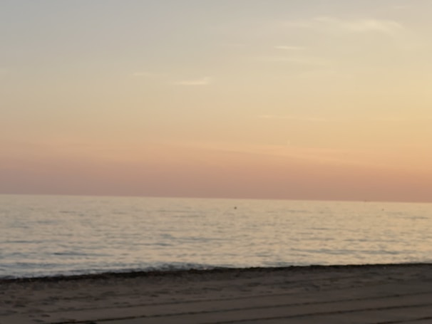 A calm beach scene with gentle waves and a pastel-colored sunset sky.
