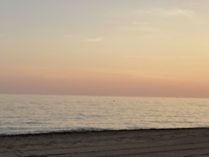 A dreamy travel snapshot of a pastel-colored sunset over a calm beach.