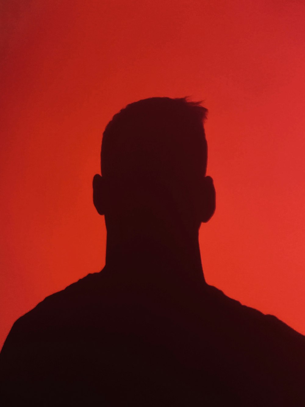 a silhouette of a man in front of a red background