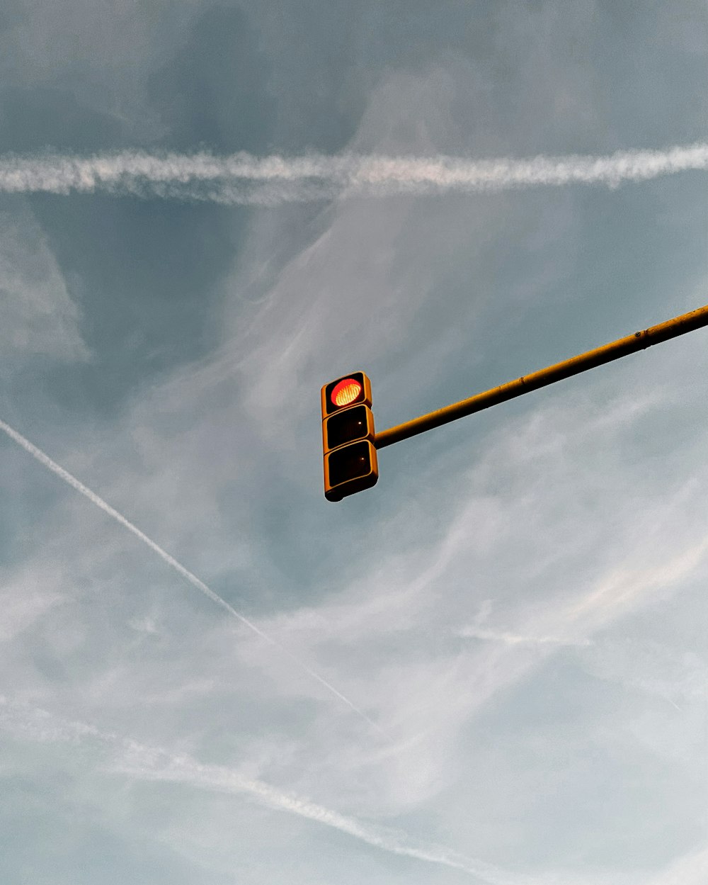 a traffic light with contrails in the sky
