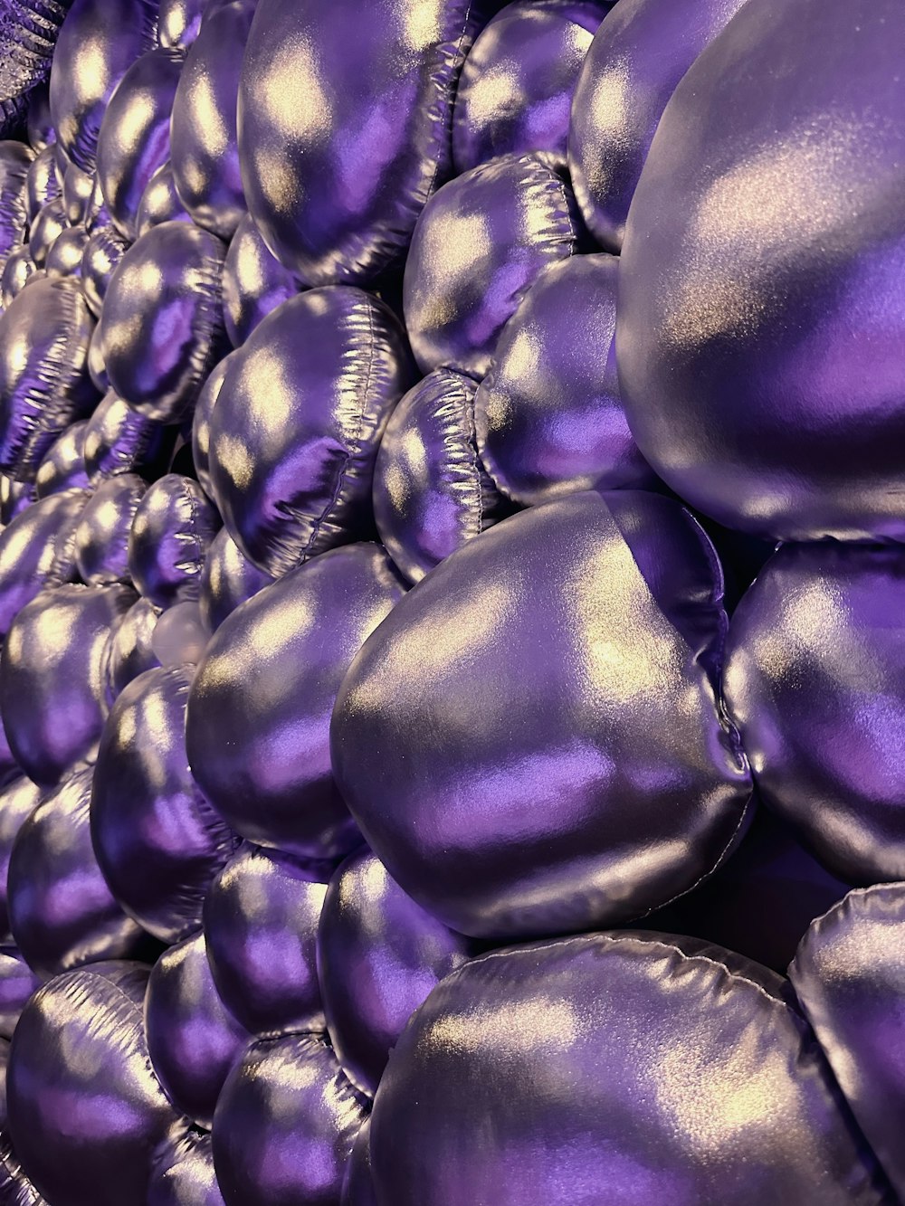 a large pile of shiny purple balloons