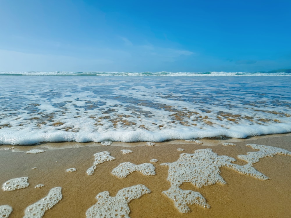 a sandy beach with waves coming in and out of the water