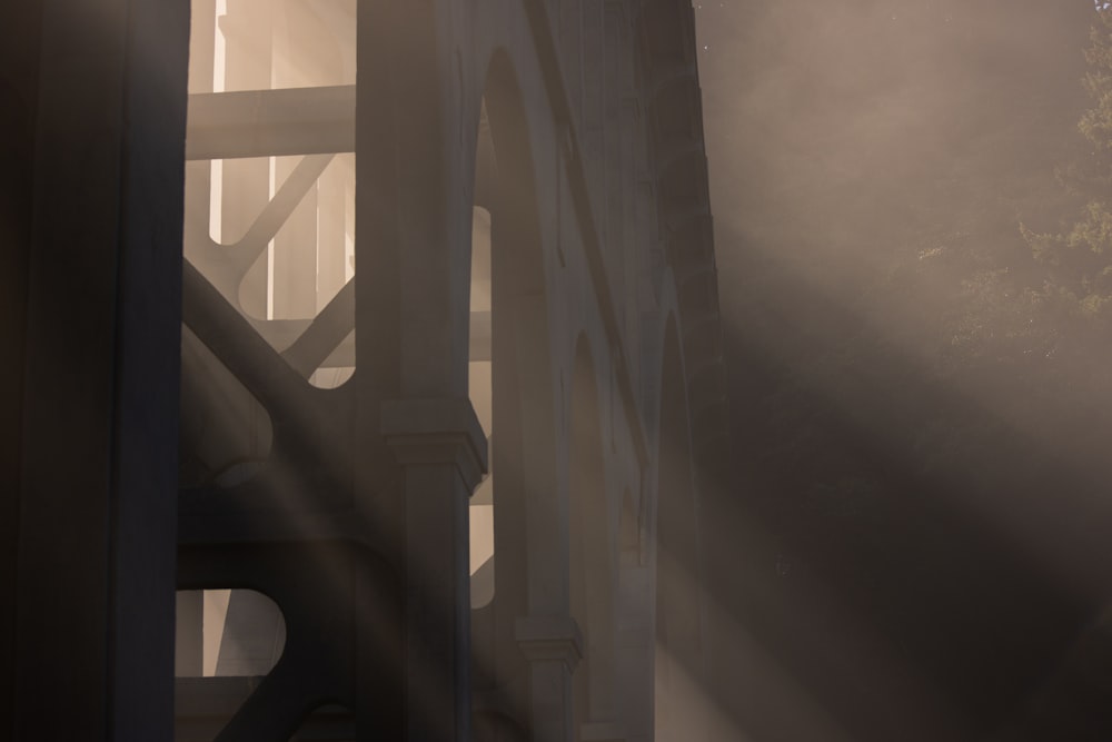the sun is shining through the fog on a bridge
