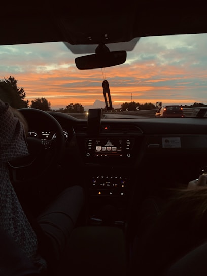 A sleek car dashboard with a mounted dashcam capturing the road ahead during sunset.