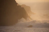 Soft morning light over rugged cliffs with gentle waves below.