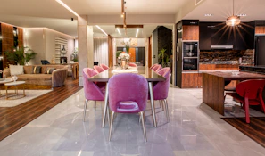 Open-plan living area with dark leather sofa and a sleek black dining table.
