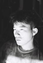 Subtle black-and-white portrait of Paulo Muhongo immersed in deep thought while writing.